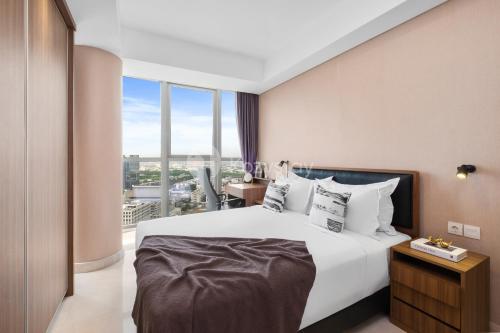 a bedroom with a large bed with a large window at Neira by Kozystay - PIK in Jakarta
