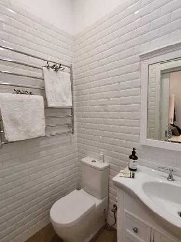 a white bathroom with a toilet and a sink at Winemakers Cottage at Treetops Red Hill in Red Hill