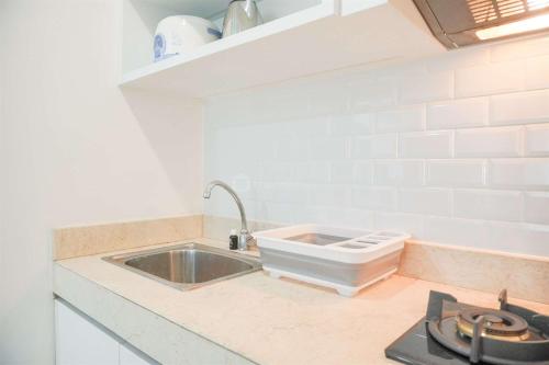 una cocina con fregadero y estufa en Modern and Homey 2BR at MT Haryono Square Apartment By Travelio, en Yakarta