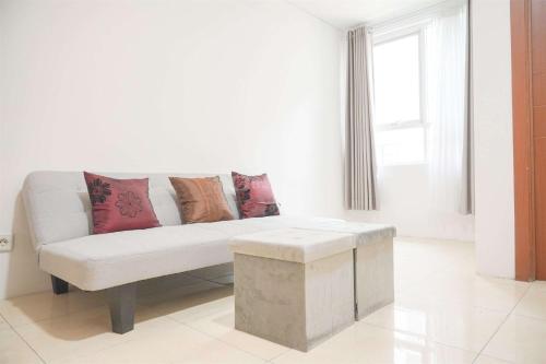 sala de estar blanca con sofá y almohadas en Modern and Homey 2BR at MT Haryono Square Apartment By Travelio, en Yakarta