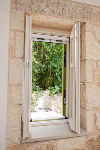 an open door with a view of a garden at Lagadia Stone House in Agios Nikitas