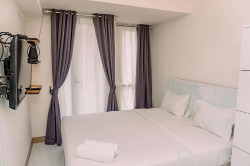 a white bed in a room with a window at Nice and Comfort Studio Apartment at Tokyo Riverside PIK 2 By Travelio in Rawalembang