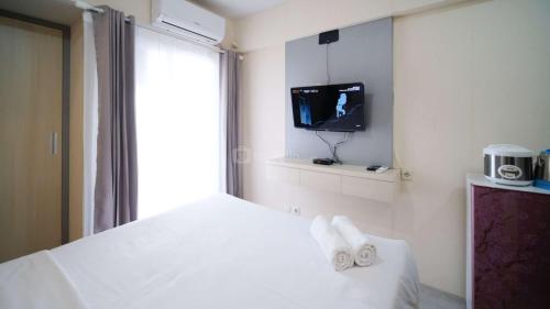 a room with a bed with a tv and towels at Best Deal and Restful Studio Apartment Suncity Residence By Travelio in Sidoarjo