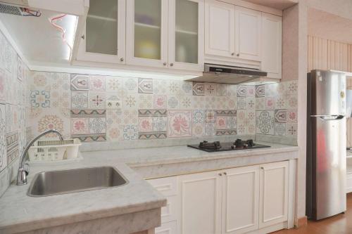a kitchen with a sink and a refrigerator at Modern and Strategic 2BR Casa De Parco Apartment near ICE BSD By Travelio in Tangerang