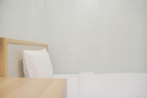 a room with white walls and a wooden table at Comfort Stay 2BR at Sky House BSD Apartment By Travelio in Tangerang