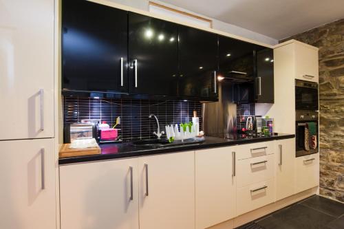 a kitchen with white cabinets and black appliances at CWTCH APARTMENT by the sea in Aberystwyth