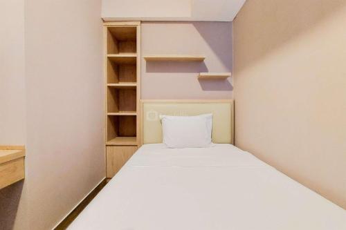 a small bedroom with a white bed and shelves at Homey and Modern 2BR at Casa de Parco Apartment By Travelio in Tangerang