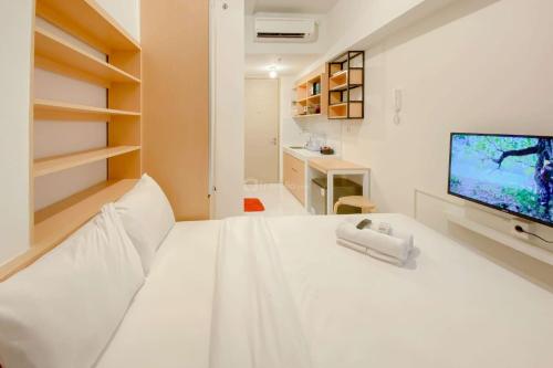 ein weißes Schlafzimmer mit einem großen weißen Bett und einem Fernseher in der Unterkunft Cozy Studio Apartment Tokyo Riverside PIK 2 By Travelio in Rawalembang