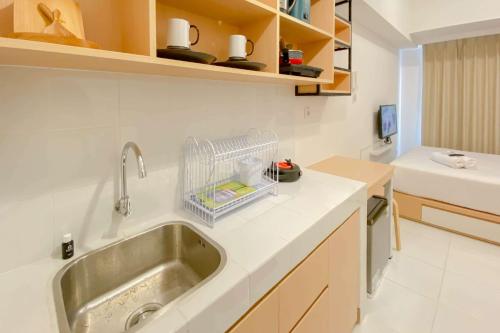 eine Küche mit einem Waschbecken und ein Zimmer mit einem Bett in der Unterkunft Cozy Studio Apartment Tokyo Riverside PIK 2 By Travelio in Rawalembang