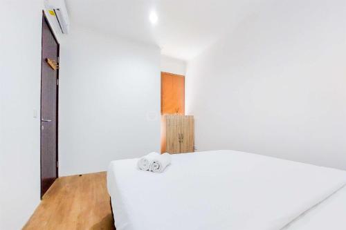 a bedroom with a white bed with two towels on it at Comfy and Modern Look 2BR Asatti Apartment By Travelio in Tangerang