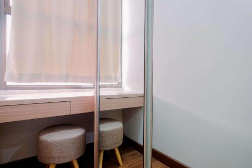 a room with two stools next to a window at Best Deal and Comfort Designed 2BR Transpark Cibubur Apartment By Travelio in Depok