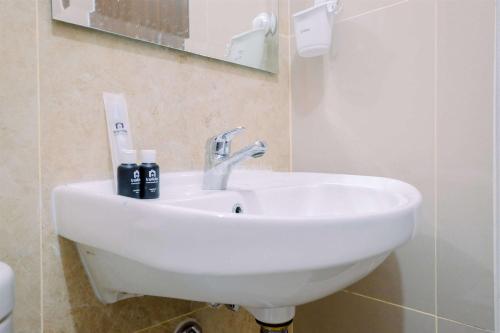 a white sink in a bathroom with a mirror at Best Deal and Comfort Designed 2BR Transpark Cibubur Apartment By Travelio in Depok