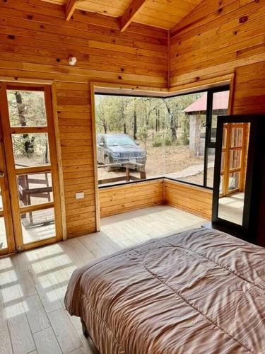 a bedroom with a bed and a view of a car outside at Cabaña Rincón del Bosque en Durango in Llano Grande
