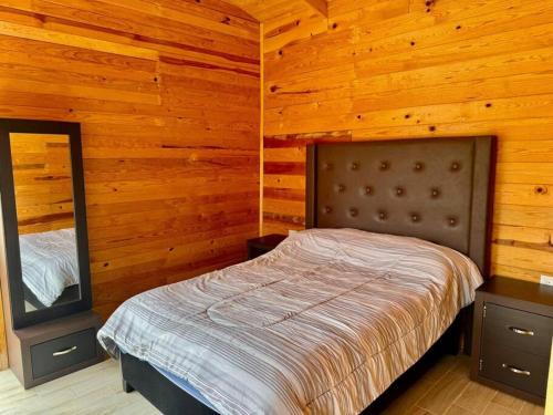 a bedroom with a bed in a wooden room at Cabaña Rincón del Bosque en Durango in Llano Grande