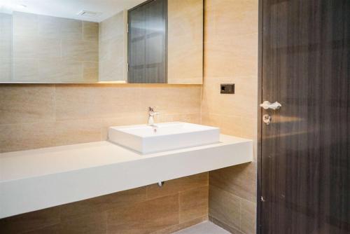 a bathroom with a white sink and a mirror at Enjoy Living 2BR Apartment at Carstensz Residence By Travelio in Kampung Sawah