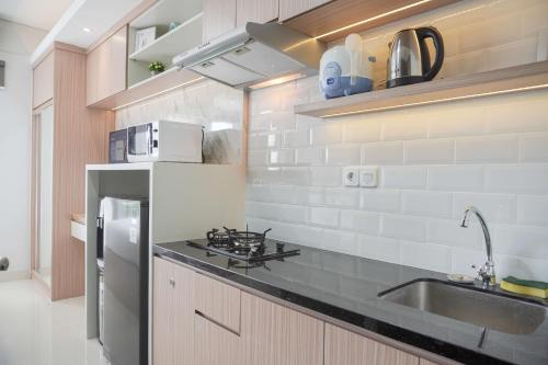 a kitchen with a sink and a stove top oven at Warm and Minimalist Studio Transpark Bintaro Apartment By Travelio in Tangerang