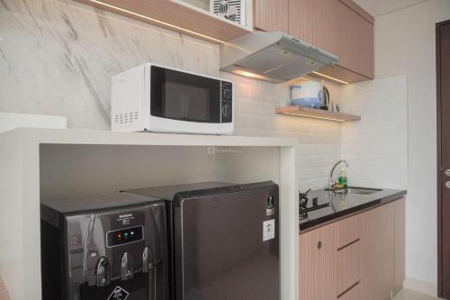 a kitchen with a microwave and a refrigerator at Warm and Minimalist Studio Transpark Bintaro Apartment By Travelio in Tangerang