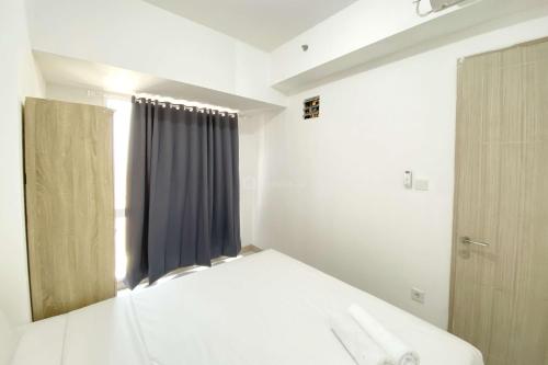 a white bedroom with a bed and a window at Comfortable 2BR at Tokyo Riverside PIK 2 Apartment By Travelio in Rawalembang