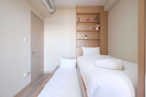 two beds in a small room with white sheets at Spacious 2BR Combined Tokyo Riverside PIK 2 Apartment By Travelio in Rawalembang