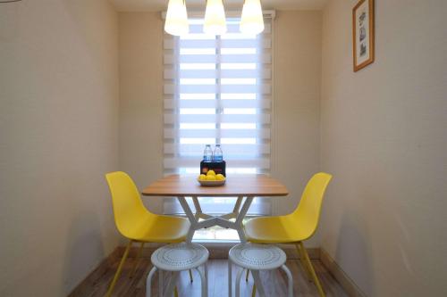 a dining room table with yellow chairs and a window at Spacious 2BR Combined Tokyo Riverside PIK 2 Apartment By Travelio in Rawalembang