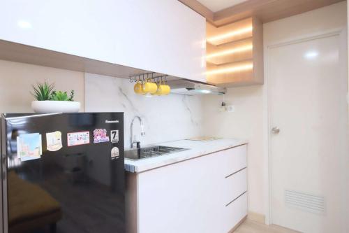 a small kitchen with a black and white refrigerator at Spacious 2BR Combined Tokyo Riverside PIK 2 Apartment By Travelio in Rawalembang