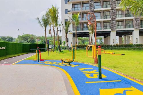 a playground in a park in front of a building at Comfort Stay 2BR at Sky House BSD Apartment near AEON By Travelio in Tangerang