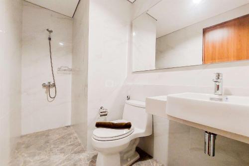 a white bathroom with a toilet and a sink at Comfort Living and Homey 1BR The Smith Alam Sutera Apartment By Travelio in Tangerang