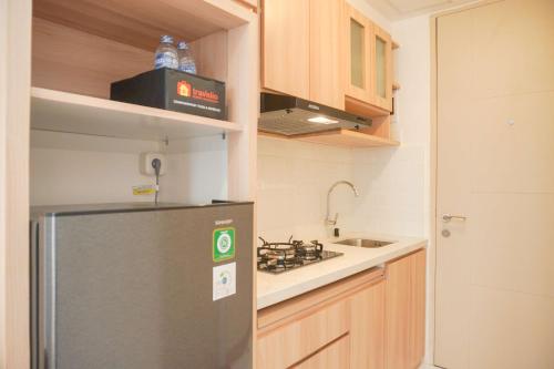 a kitchen with a stainless steel refrigerator and a sink at Fully Furnished with Cozy Design Studio Tokyo Riverside PIK 2 Apartment By Travelio in Rawalembang