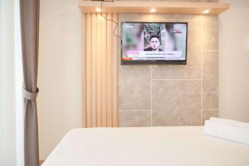a bedroom with a television on a wall at Fully Furnished with Cozy Design Studio Tokyo Riverside PIK 2 Apartment By Travelio in Rawalembang