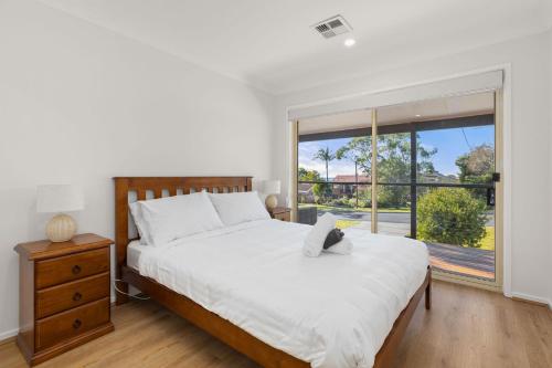 Un dormitorio con una cama grande y una ventana grande. en White Sands Retreat by Experience Jervis Bay, en Vincentia