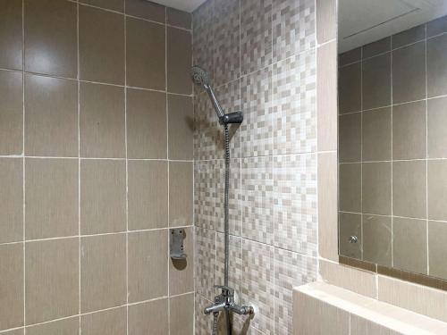 a shower in a tiled bathroom with at Cozy and Enjoy Living Studio Enviro Apartment By Travelio in Cikarang