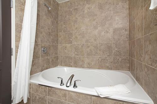 a bath tub in a bathroom with a shower at Travelodge by Wyndham Wetaskiwin in Wetaskiwin