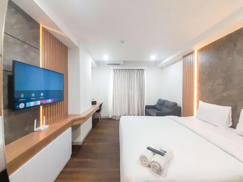Una habitación de hotel con una cama y un televisor de pantalla plana. en Tranquil and Modern Studio at Mataram City Apartment By Travelio, en Kejayan