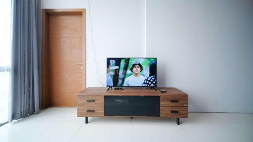 a tv sitting on top of a wooden dresser in a room at Best Choice and Spacious 1BR Apartment at Aryaduta Residence Surabaya By Travelio in Surabaya