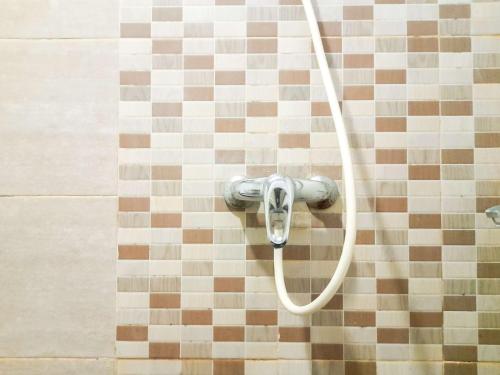 eine Dusche mit einem Schlauch auf einem Fliesenboden in der Unterkunft Homey and Warm 1BR at Student Castle Yogyakarta Apartment By Travelio in Seturan