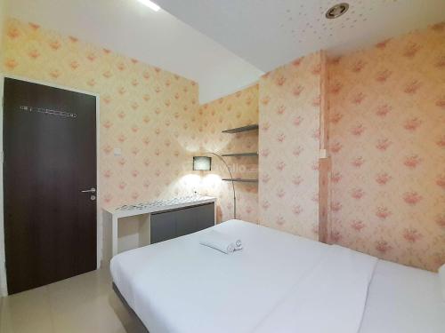 ein Schlafzimmer mit einem weißen Bett und einer schwarzen Tür in der Unterkunft Homey and Warm 1BR at Student Castle Yogyakarta Apartment By Travelio in Seturan