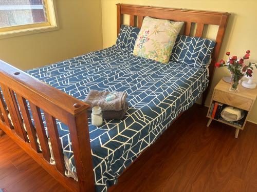 a bedroom with a bed with a blue and white bedspread at Wellness Stay in Private Home near beaches, rainforest and South Coast, 2 rooms booked separately in Dapto