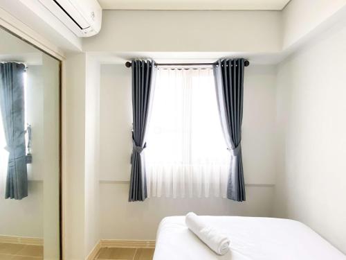 a bedroom with a bed and a window at Best Deal and Cozy 3BR Meikarta Apartment By Travelio in Cikarang