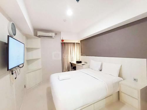 a bedroom with a white bed and a flat screen tv at Good Choice and Modern Studio Marquis de Lafayette Apartment By Travelio in Semarang