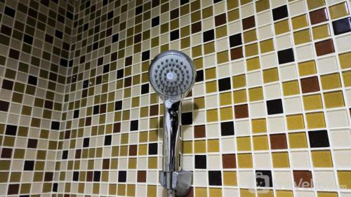 a shower head on a tiled wall in a bathroom at Spacious 2BR with Access to Mall at Aryaduta Residence Surabaya Apartment By Travelio in Surabaya