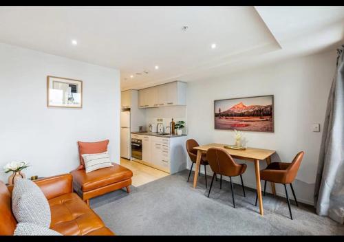 a living room with a couch a table and a kitchen at Stylish Modern Unit w Balcony and Pool Zodiak Stays in Auckland