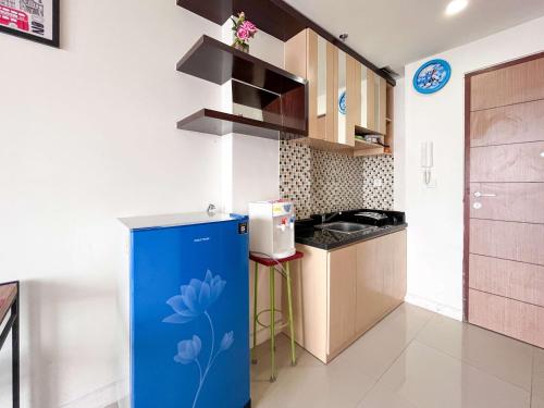 a kitchen with a blue refrigerator in a room at Compact 2BR at Apartemen Vida View Makassar by Travelio in Pampang