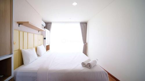 a bedroom with a large white bed with a window at Best Location and Strategic 2BR at Praxis Apartment By Travelio in Surabaya