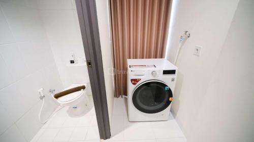 a bathroom with a washing machine and a toilet at Best Location and Strategic 2BR at Praxis Apartment By Travelio in Surabaya