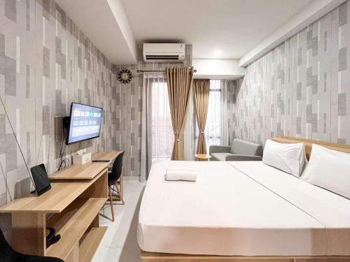 a bedroom with a bed and a desk and a tv at Best Deal Studio Room at Delft Ciputra Makassar Apartment By Travelio in Sungguminasa