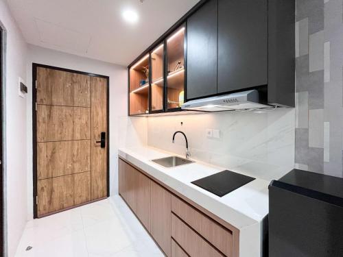 a kitchen with a sink and a wooden door at Best Deal Studio Room at Delft Ciputra Makassar Apartment By Travelio in Sungguminasa