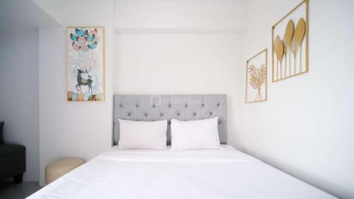 a white bedroom with a large bed with white sheets at Well Furnished and Homey Studio (No Kitchen) Apartment at Suncity Residence By Travelio in Sidoarjo