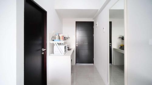 a hallway with a black door in a white kitchen at Well Furnished and Homey Studio (No Kitchen) Apartment at Suncity Residence By Travelio in Sidoarjo