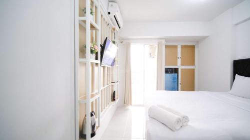 a white bedroom with a white bed and a window at New Studio Apartment with Strategic Location at Suncity Residence By Travelio in Sidoarjo