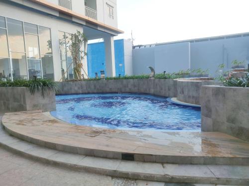 a swimming pool in front of a building at Homey and Comfy 2BR Apartment at Suncity Residence By Travelio in Sidoarjo